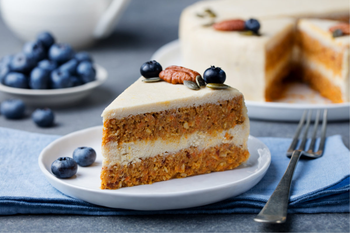 Vegan carrot cake on a table with a fork. Our vegan baking guide will help create tasty vegan bakes.