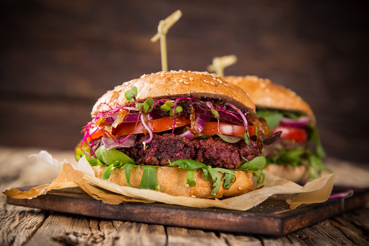 Close-up of home made vegetarian red beet burgers on wooden table.