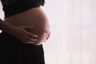 A woman holding her pregnant belly. Lots of vegan women wonder if a vegan pregnancy is safe.