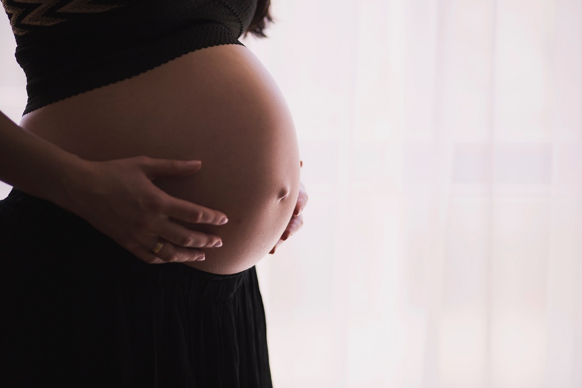 A woman holding her pregnant belly. Lots of vegan women wonder if a vegan pregnancy is safe.