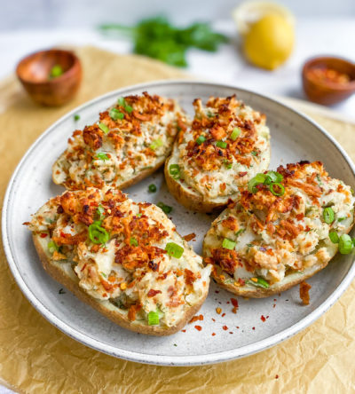Four baked potatoes topped with Mind Blown Crab Cakes on top