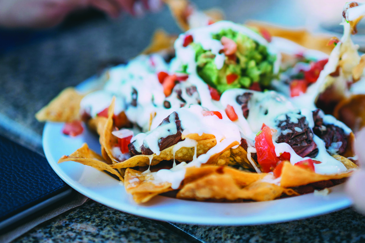 Vegan Super Bowl recipes idea: A dish of crunchy golden tortilla is covered in all the nacho fixings 