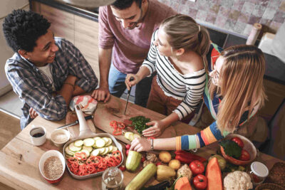 Vier Personen beim Zubereiten eines veganen Gerichts